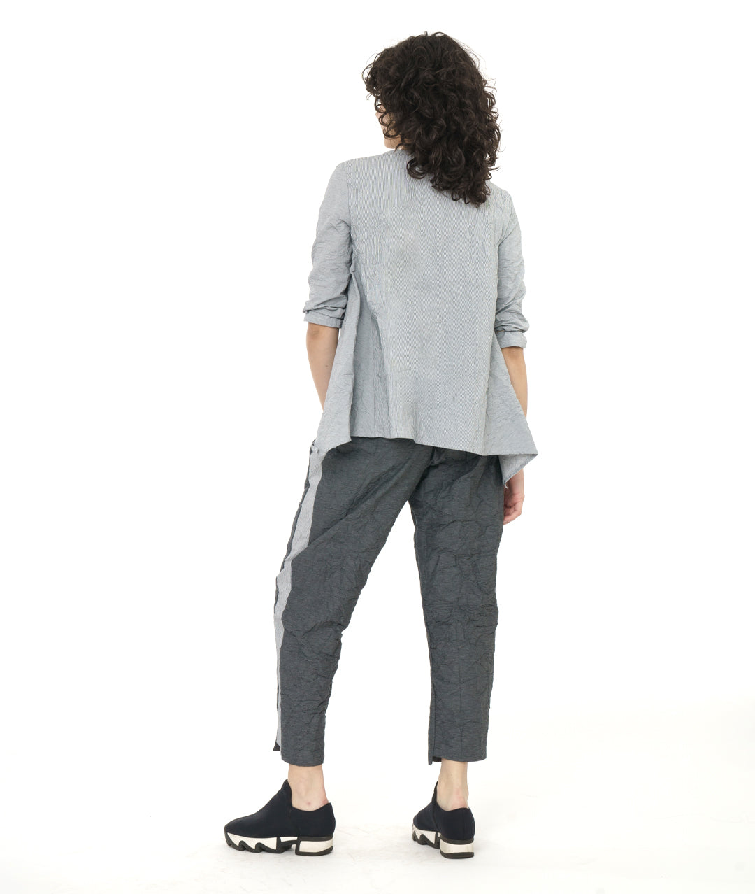 model in a grey and white pinstripe top with a crushed texture, with a matching pant in a black and grey stripe. Top has 3/4 sleeves, a single hip pocket and a full flowy body