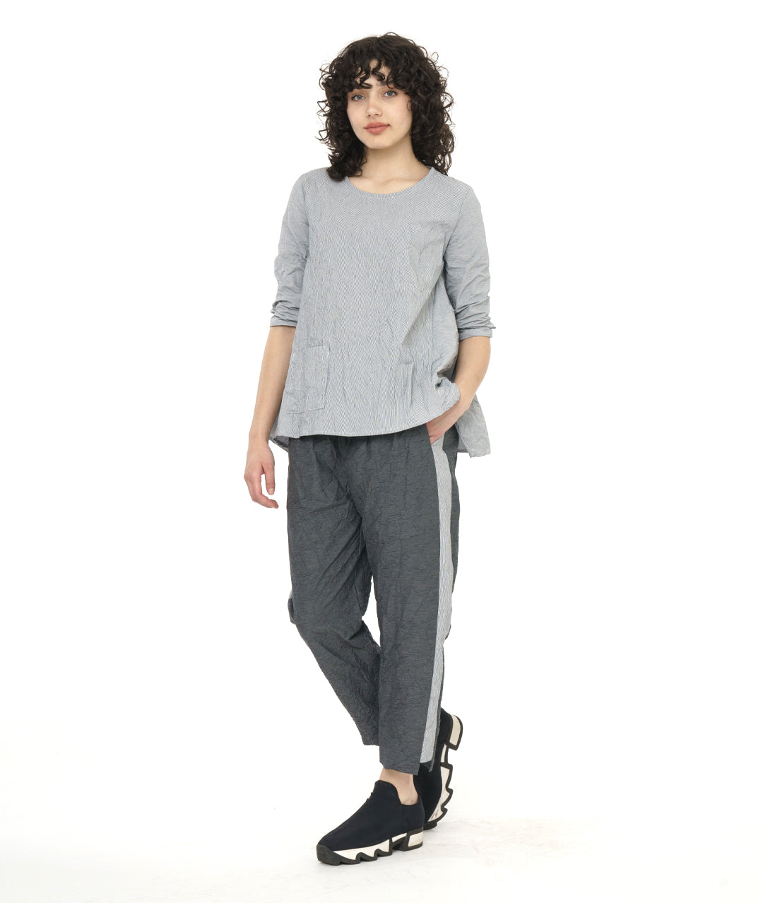 model in a grey and white pinstripe top with a crushed texture, with a matching pant in a black and grey stripe. Top has 3/4 sleeves, a single hip pocket and a full flowy body