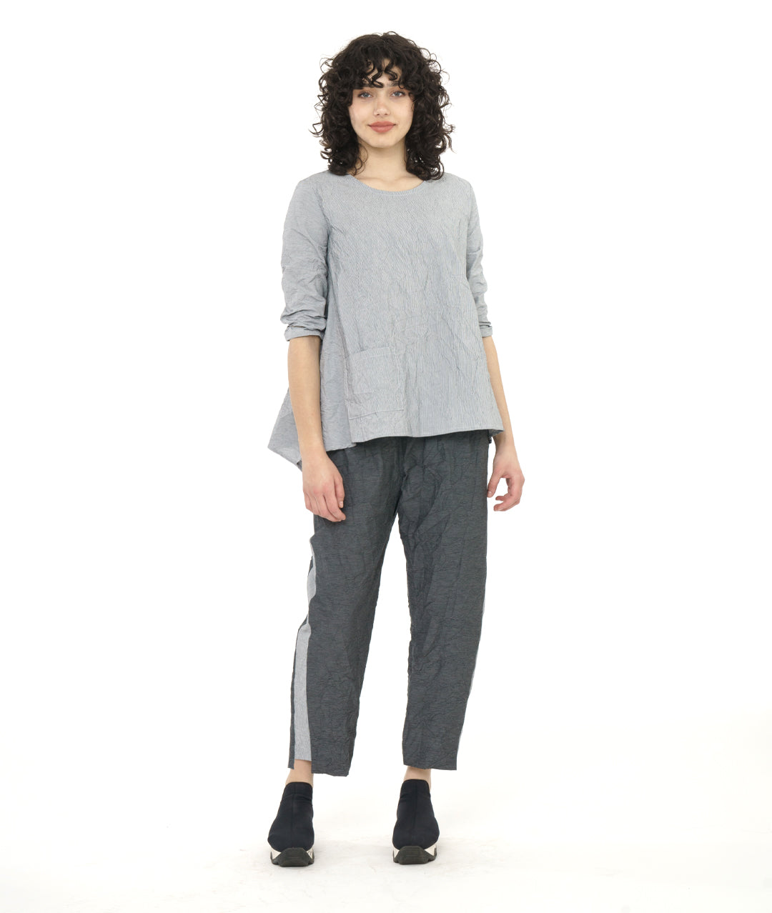 model in a grey and white pinstripe top with a crushed texture, with a matching pant in a black and grey stripe. Top has 3/4 sleeves, a single hip pocket and a full flowy body