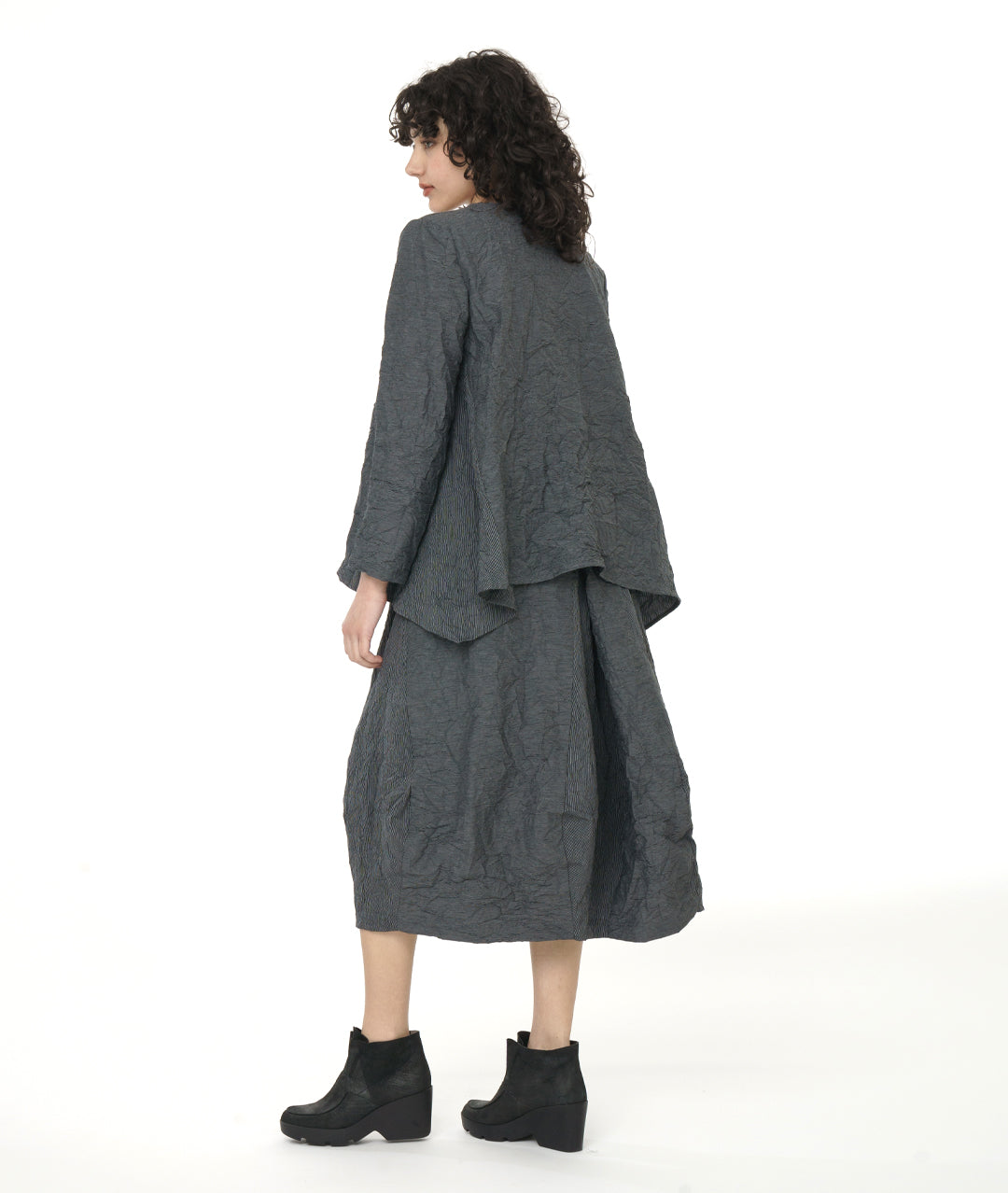model in a black and grey pinstriped skirt with a matching pullover top with long sleeves, a single squared hip pocket, round neckline and a dip in the hem at either side