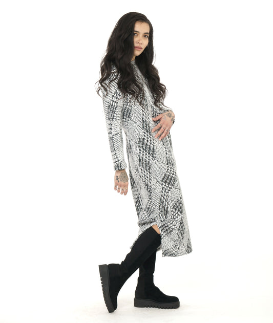 model in a black and white wavy plaid print dress with long sleeves and a split at either side of the bottom hem