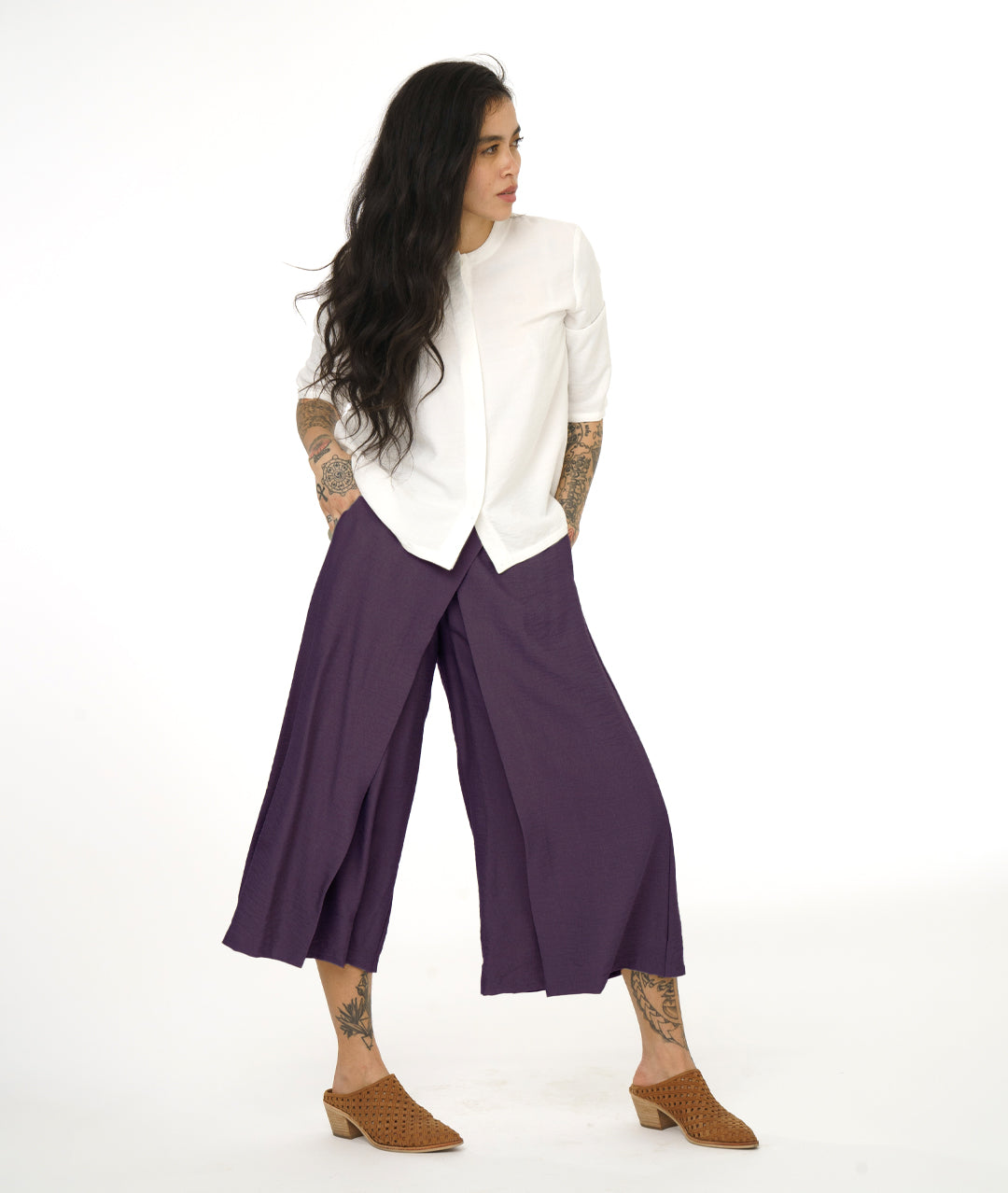 model in a white pullover top with a purple wide leg pant with overlapping layers at the front
