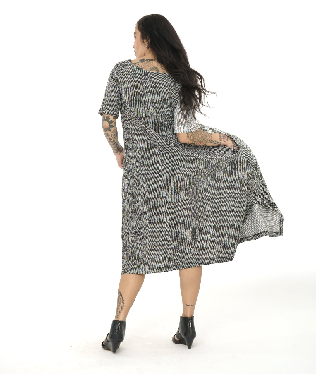 model in a black and white striped dress with contrasting panels and tucks on the sides