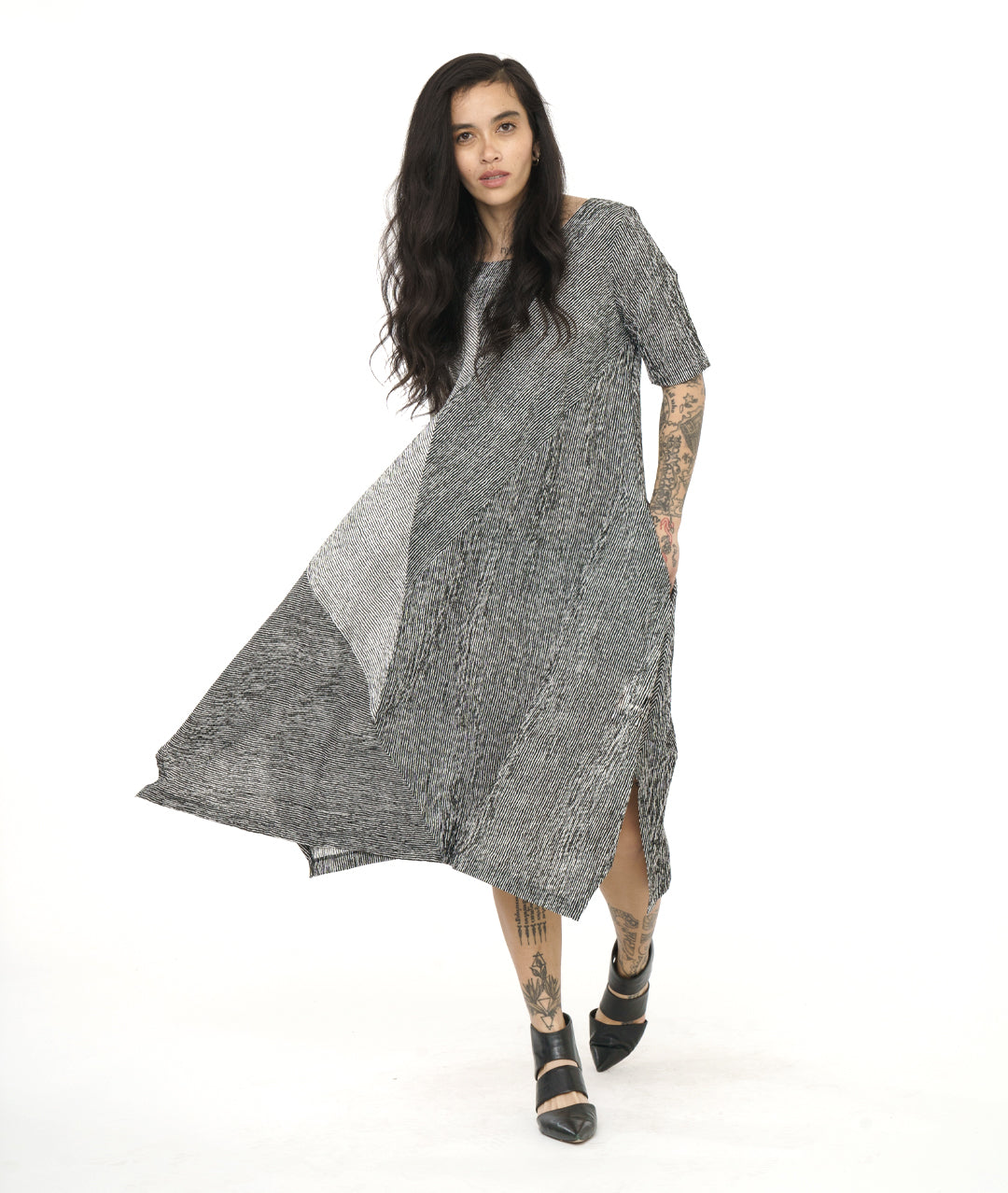 model in a black and white striped dress with contrasting panels and tucks on the sides