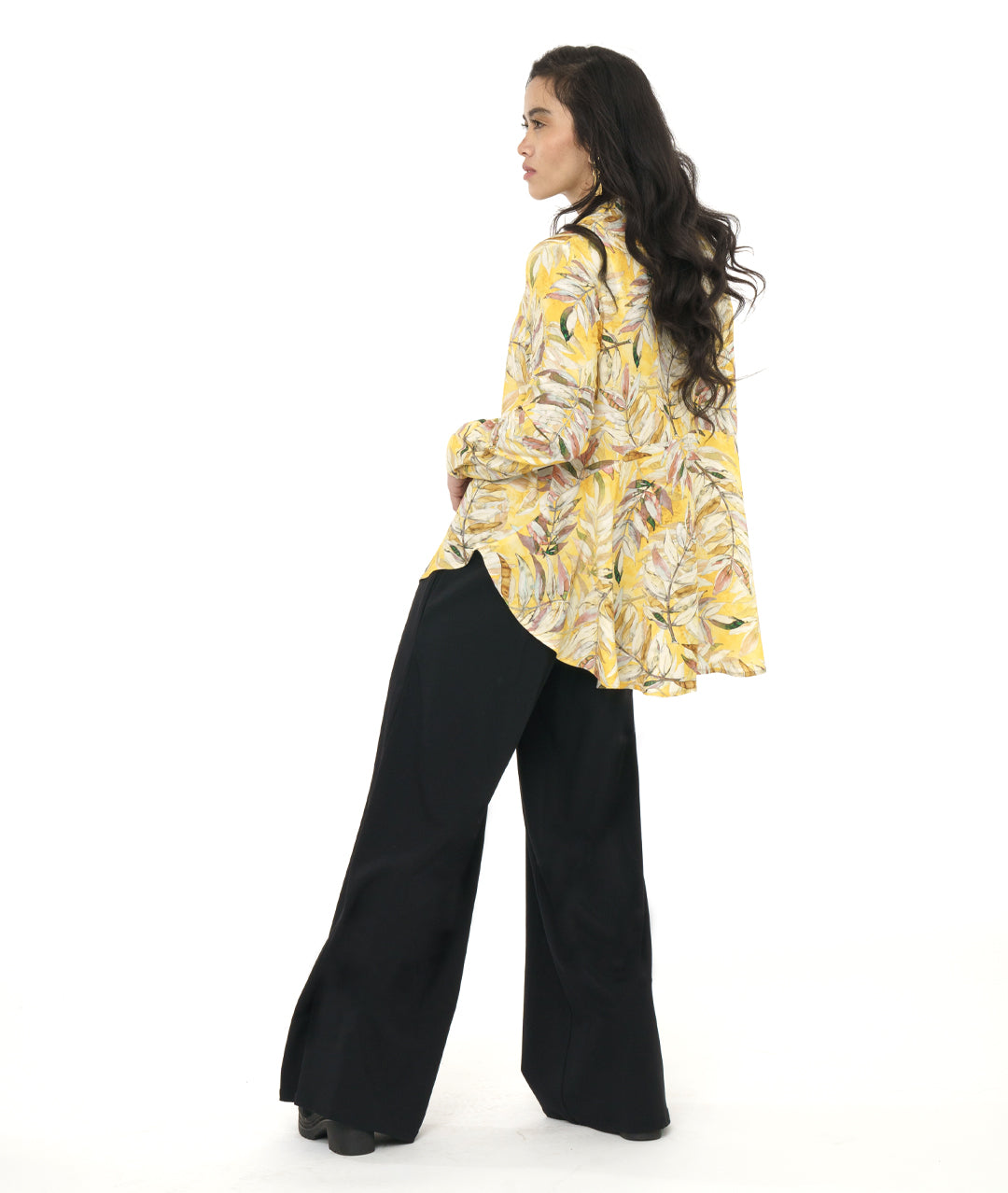model in a wide leg black pant with a yellow floral print blouse with a rounded hem, dipping lower in the back