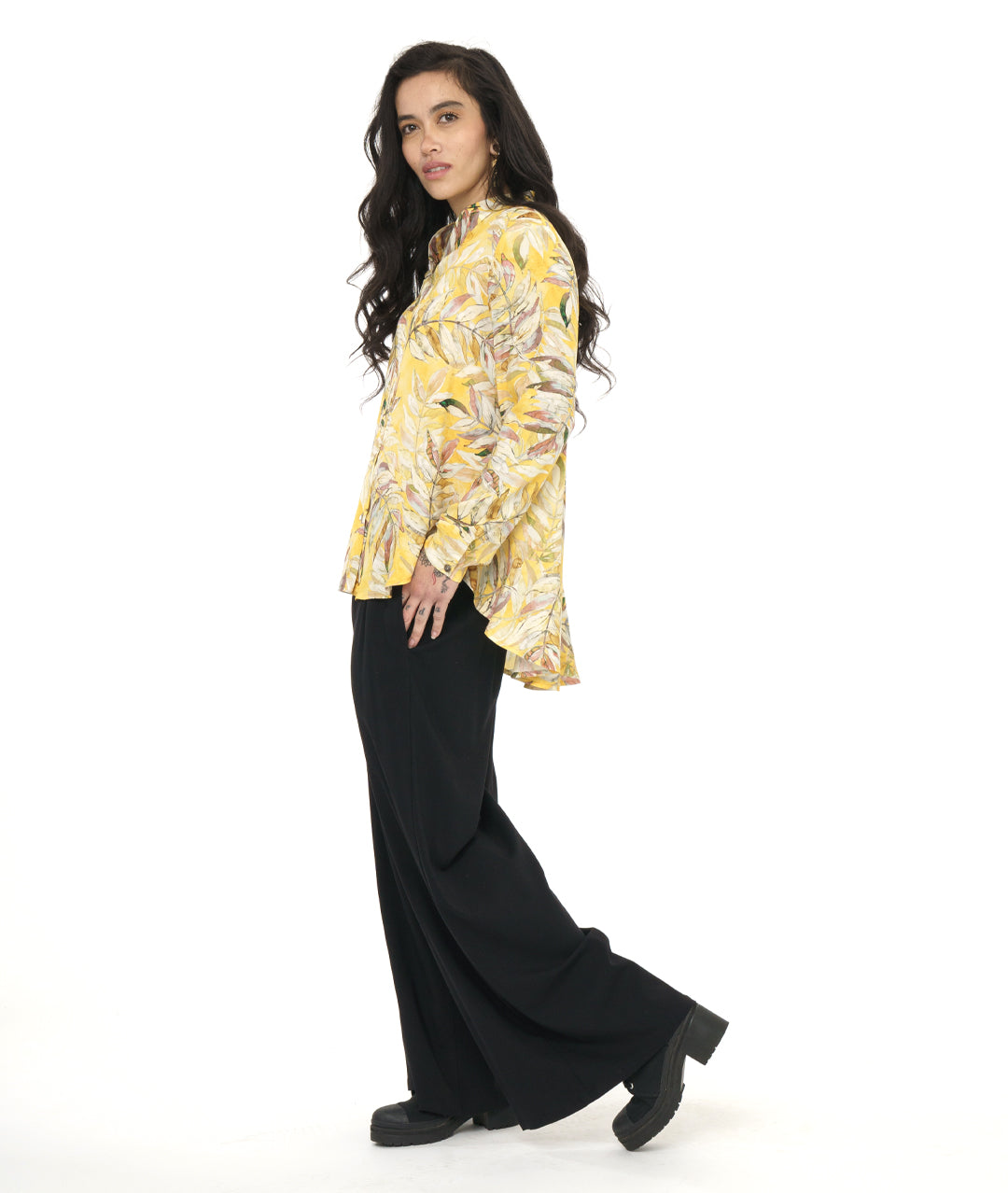 model in a wide leg black pant with a yellow floral print blouse with a rounded hem, dipping lower in the back
