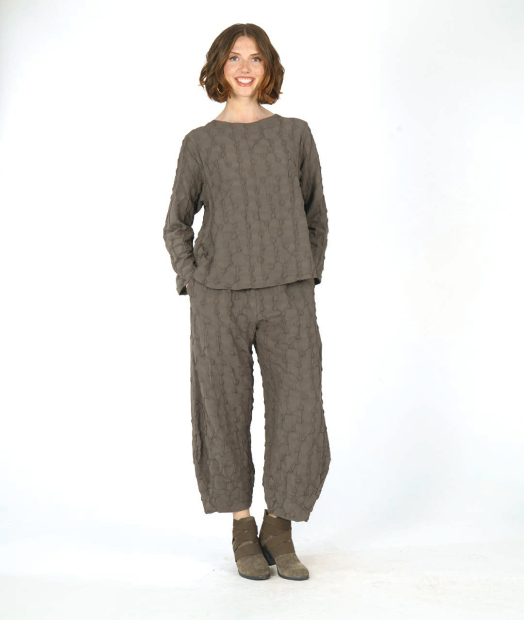 model in a wide leg green pant with a tapered ankle and a puckered dot texture, worn with a matching pullover top