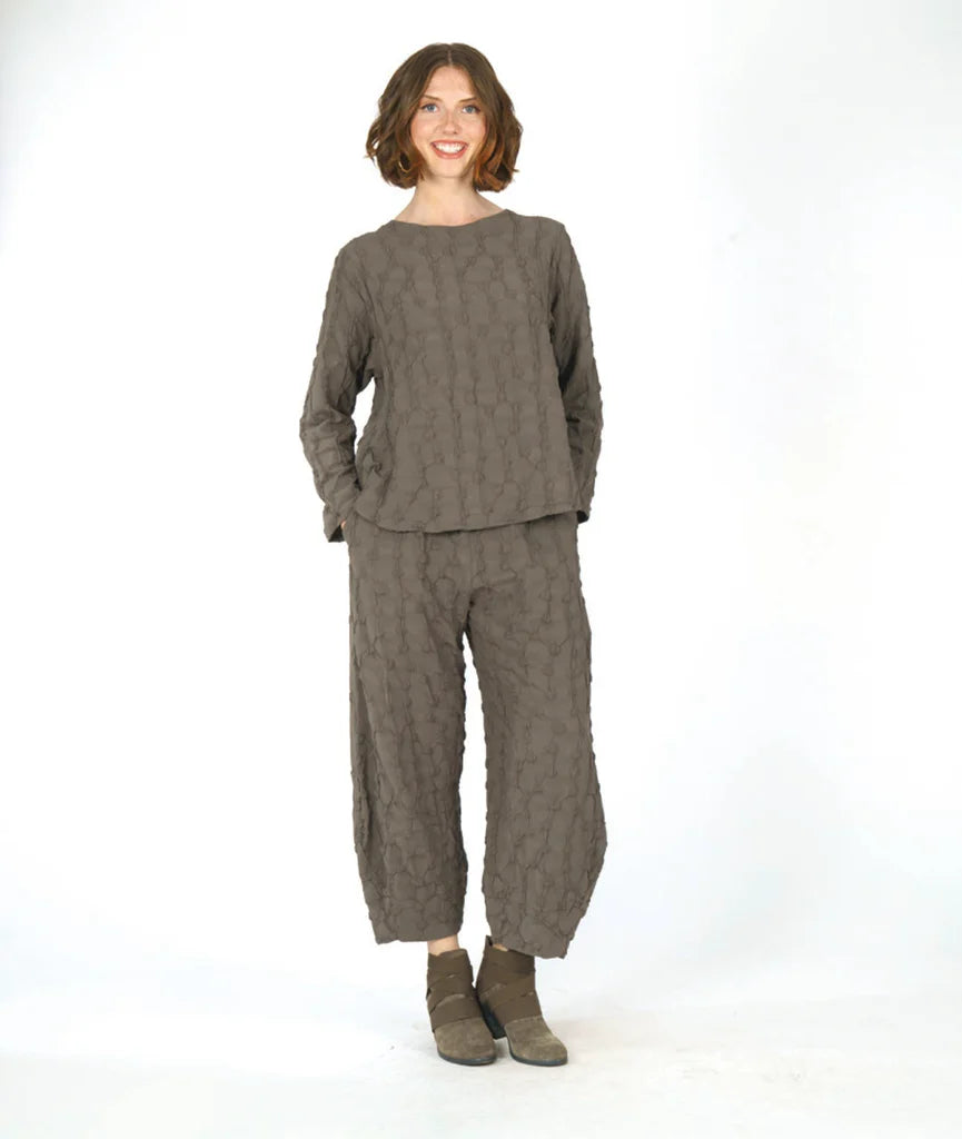 model wearing a green long sleeve top with matching wide leg pants that tapers to tulip shape at ankle on a white background