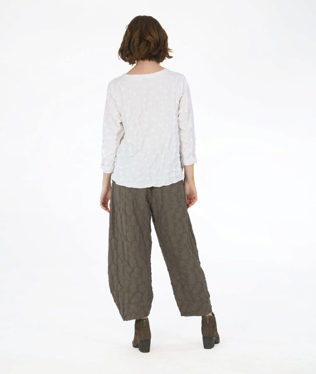 model in a wide leg green pant with a tapered ankle and a puckered dot texture, worn with a matching white pullover top