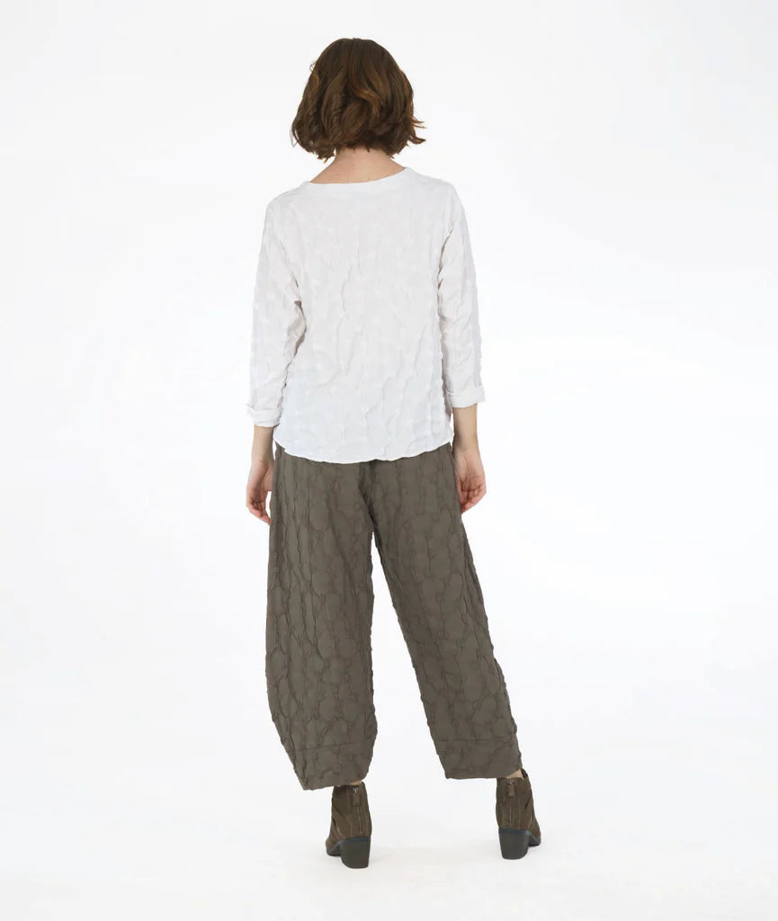 model showing back of white textured long sleeve top with green textured wide leg pants that tapers to tulip shape at ankle on a white background