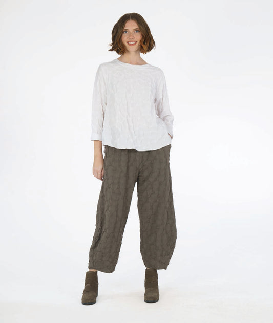 model in a wide leg green pant with a tapered ankle and a puckered dot texture, worn with a matching white pullover top