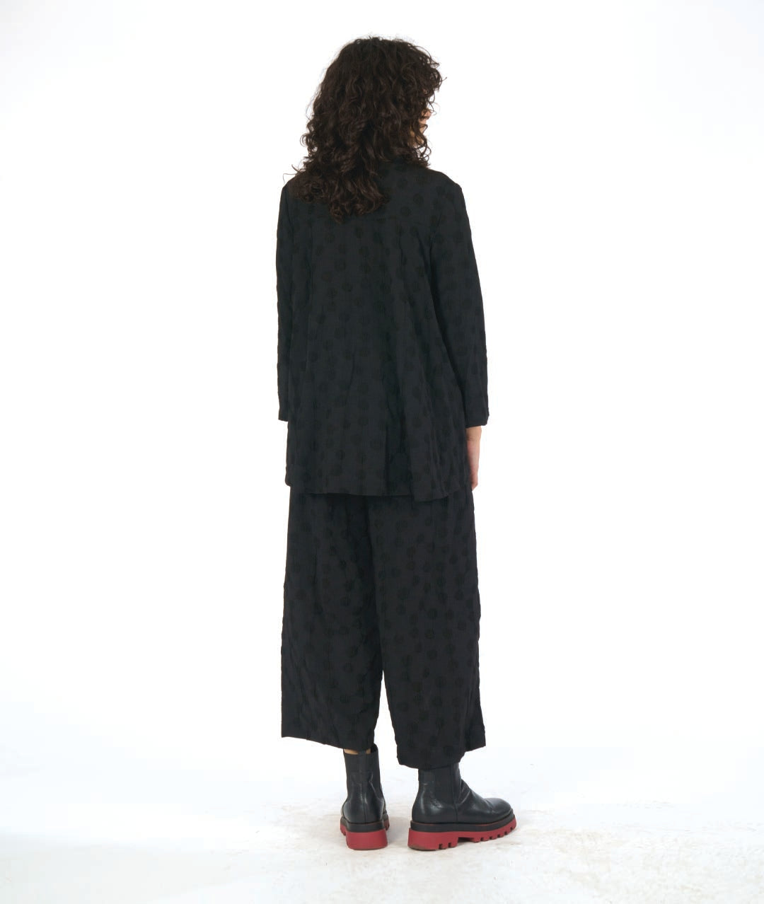 model in a wide leg black pant with a puckered dot texture, worn with a matching blouse