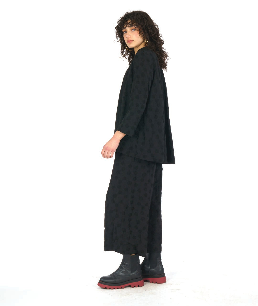 model in a wide leg black pant with a puckered dot texture, worn with a matching blouse