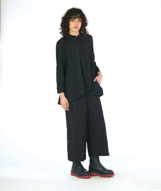 model in a wide leg black pant with a puckered dot texture, worn with a matching blouse