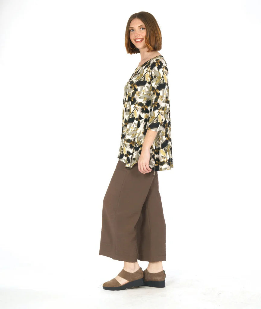 Woman wearing a floral blouse and brown pants on a white background