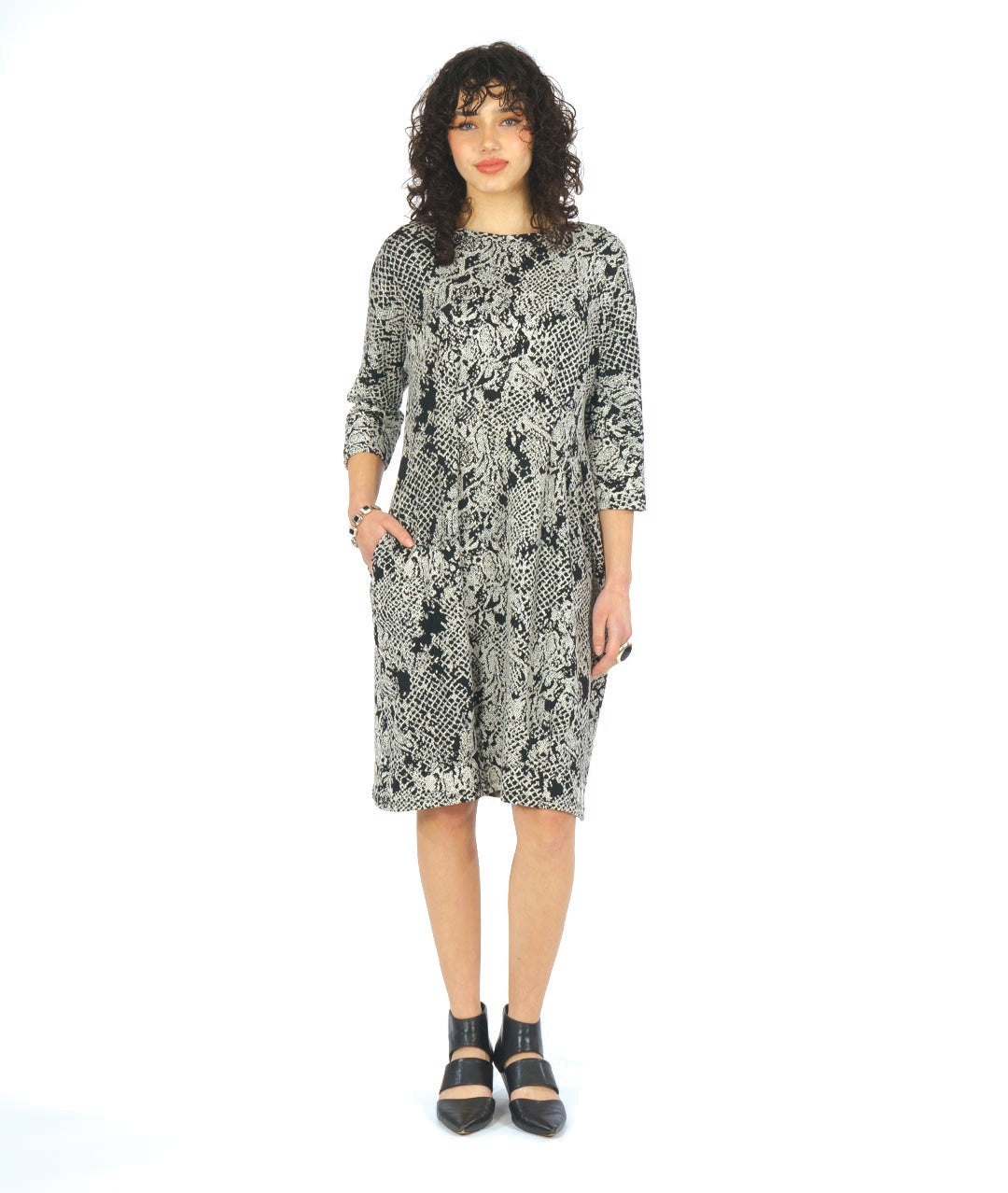 model in a black and white lace knit dress with 3/4 sleeves, pockets and shaping darts at the waist