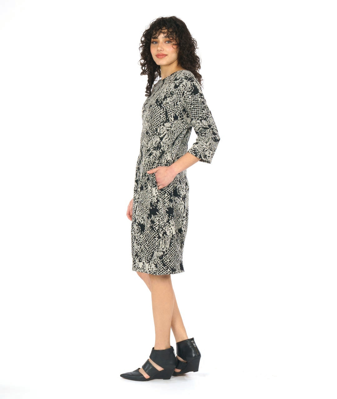 model in a black and white lace knit dress with 3/4 sleeves, pockets and shaping darts at the waist