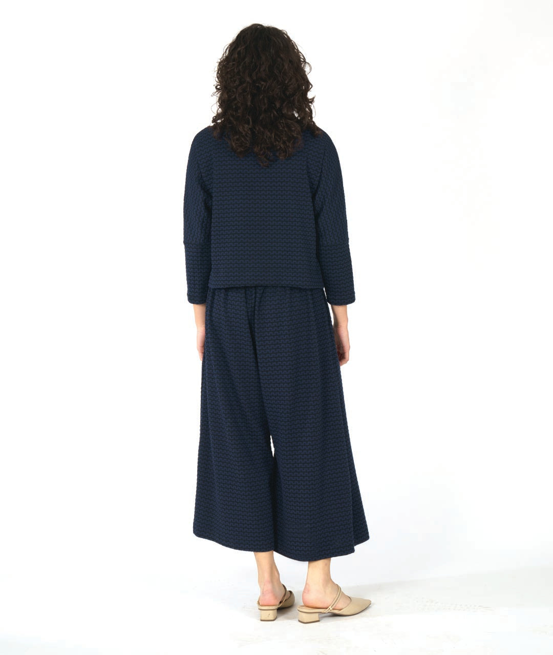 model in a black and blue zipper knit pullover top with a high neckline and dolman sleeves. worn with a matching wide leg pant