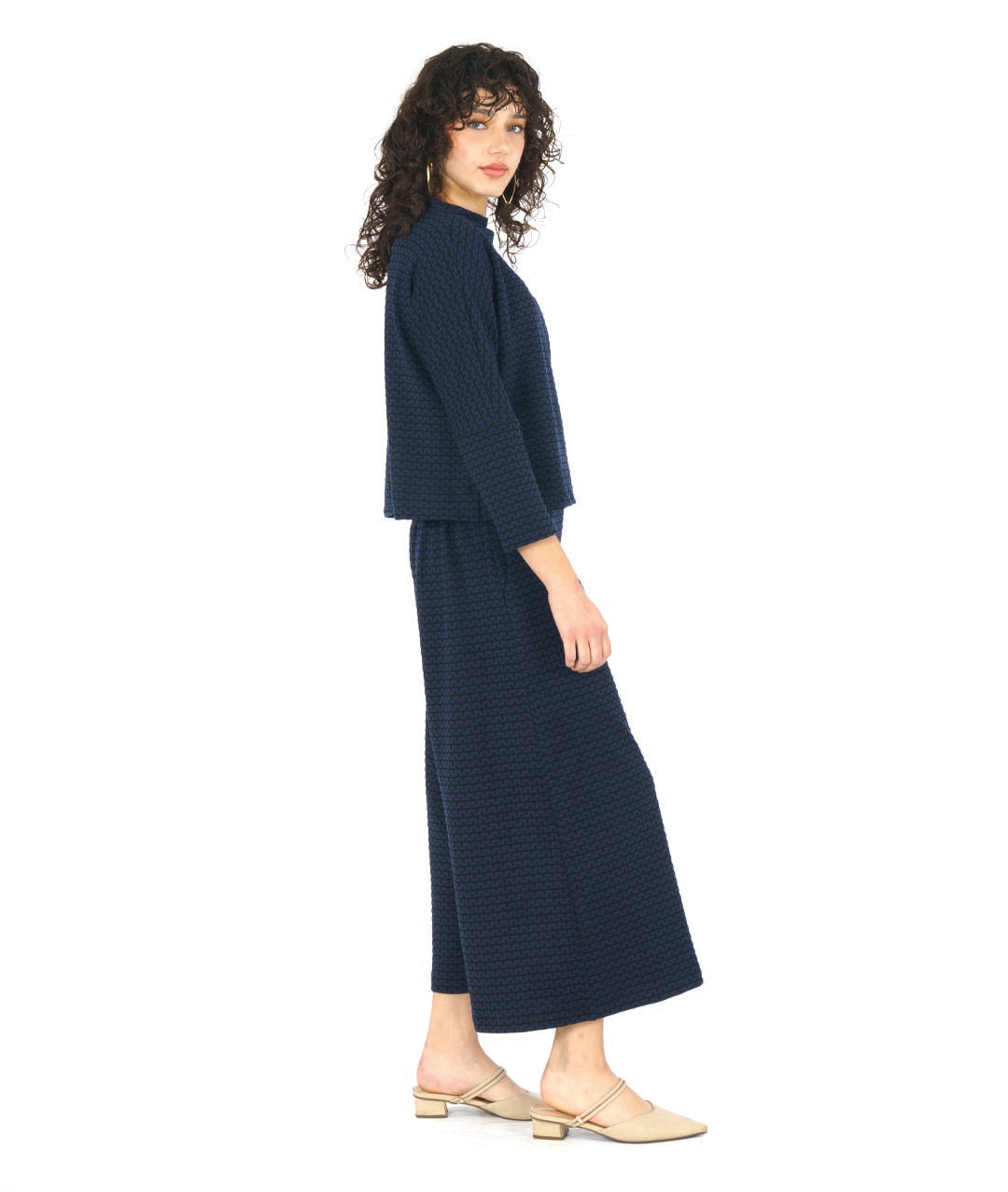 model in a black and blue zipper knit pullover top with a high neckline and dolman sleeves. worn with a matching wide leg pant