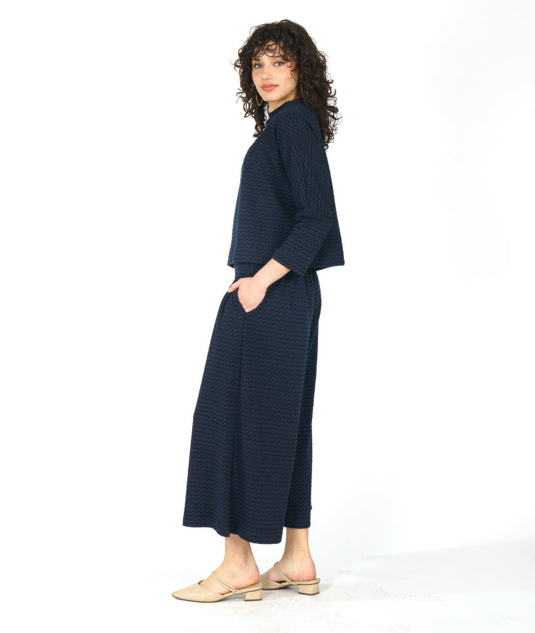 model in a black and blue zipper knit pullover top with a high neckline and dolman sleeves. worn with a matching wide leg pant
