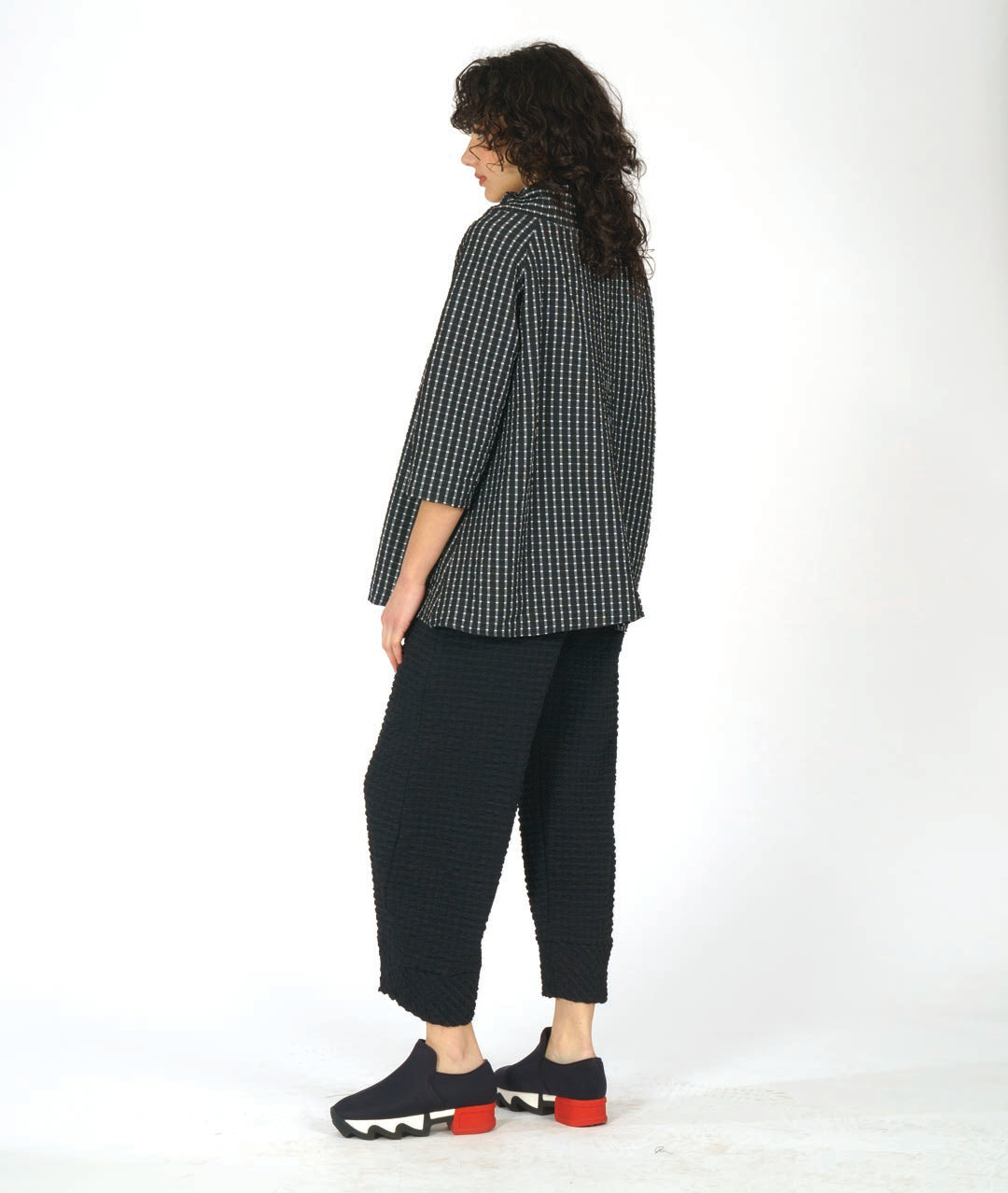 model in a wide leg black pant with a tapered ankle. worn with a black and white grid print pullover top with an oversized, gathered collar and 3/4 sleeves