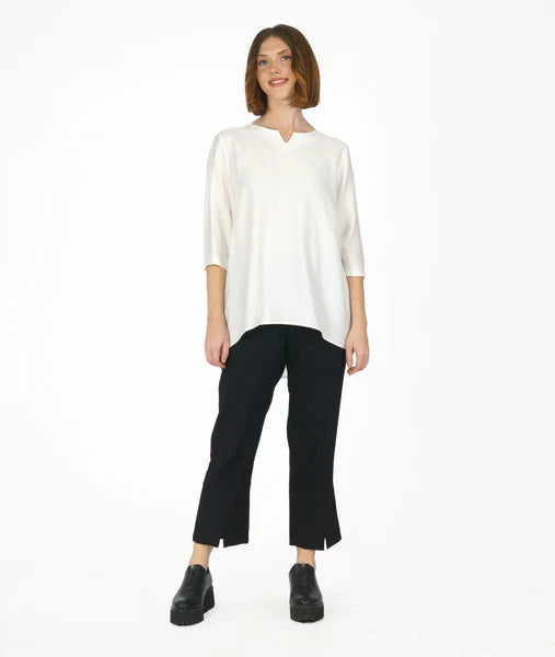model wearing 3/4 sleeve white top with black slim leg pants with slit at the ankle