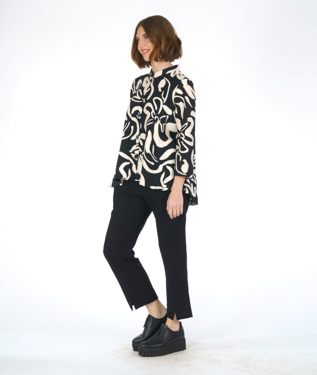 model in a straight cut black pant with a black and ivory floral print blouse with 3/4 sleeves, a mandarin style collar, and black and white buttons down the center front.