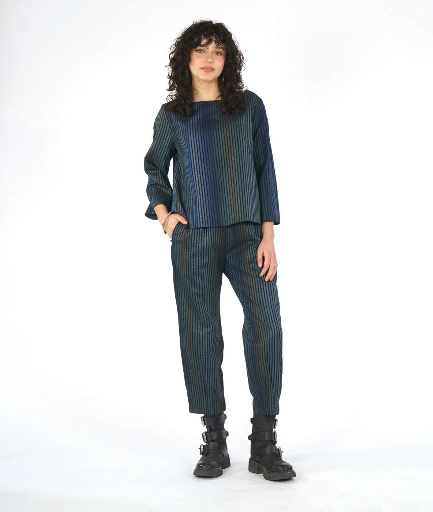 model wearing a dark blue striped outfit with black boots on a white background