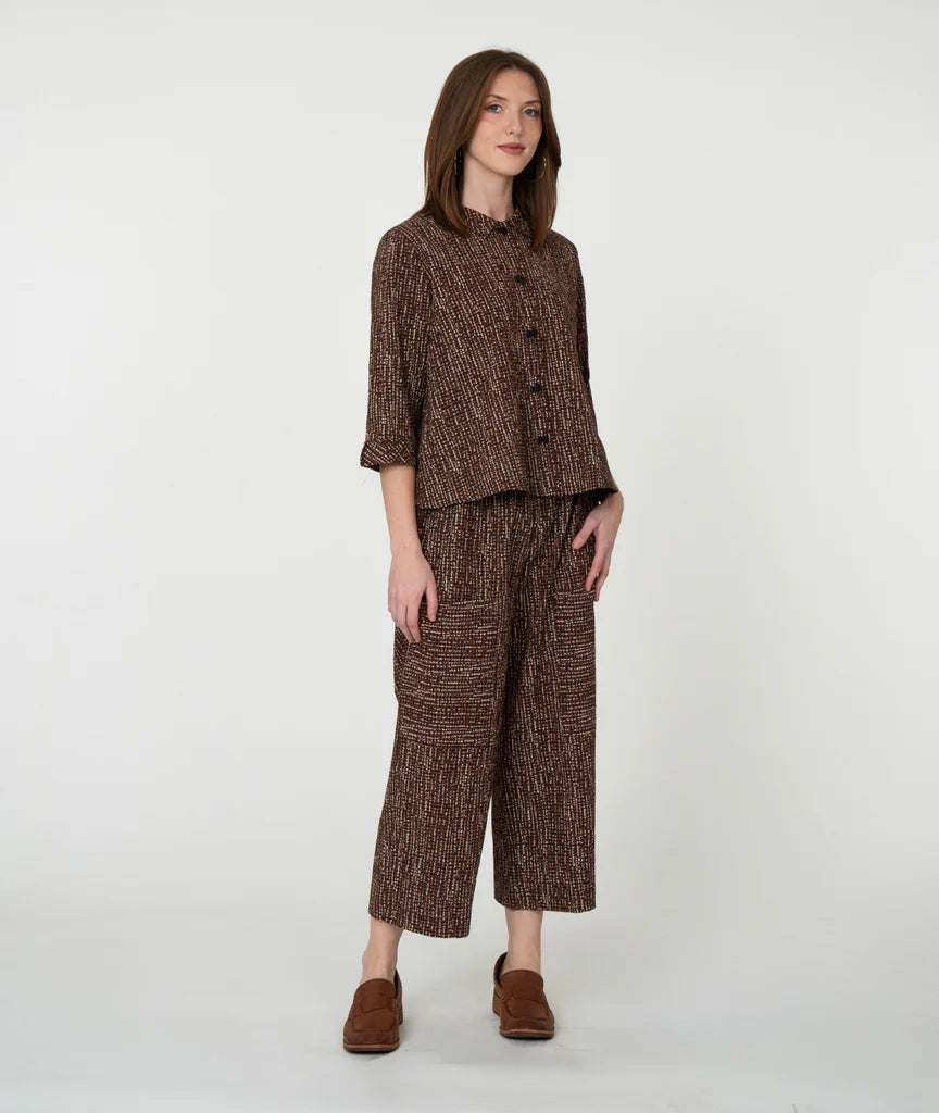Woman wearing a brown patterned outfit on a white background