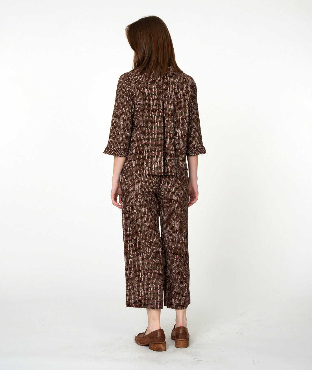 Woman wearing a brown patterned outfit on a white background