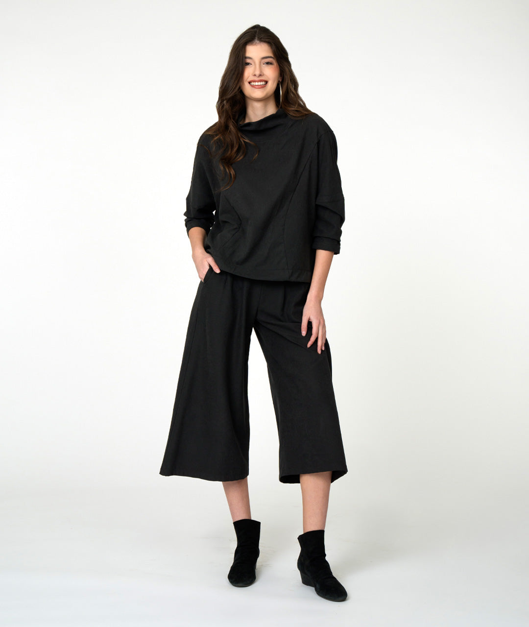 model wearing black cowl 3/4 sleeve top with wide-leg black pants and black shoes