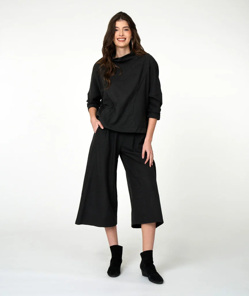 model wearing black cowl 3/4 sleeve top with wide-leg black pants and black shoes