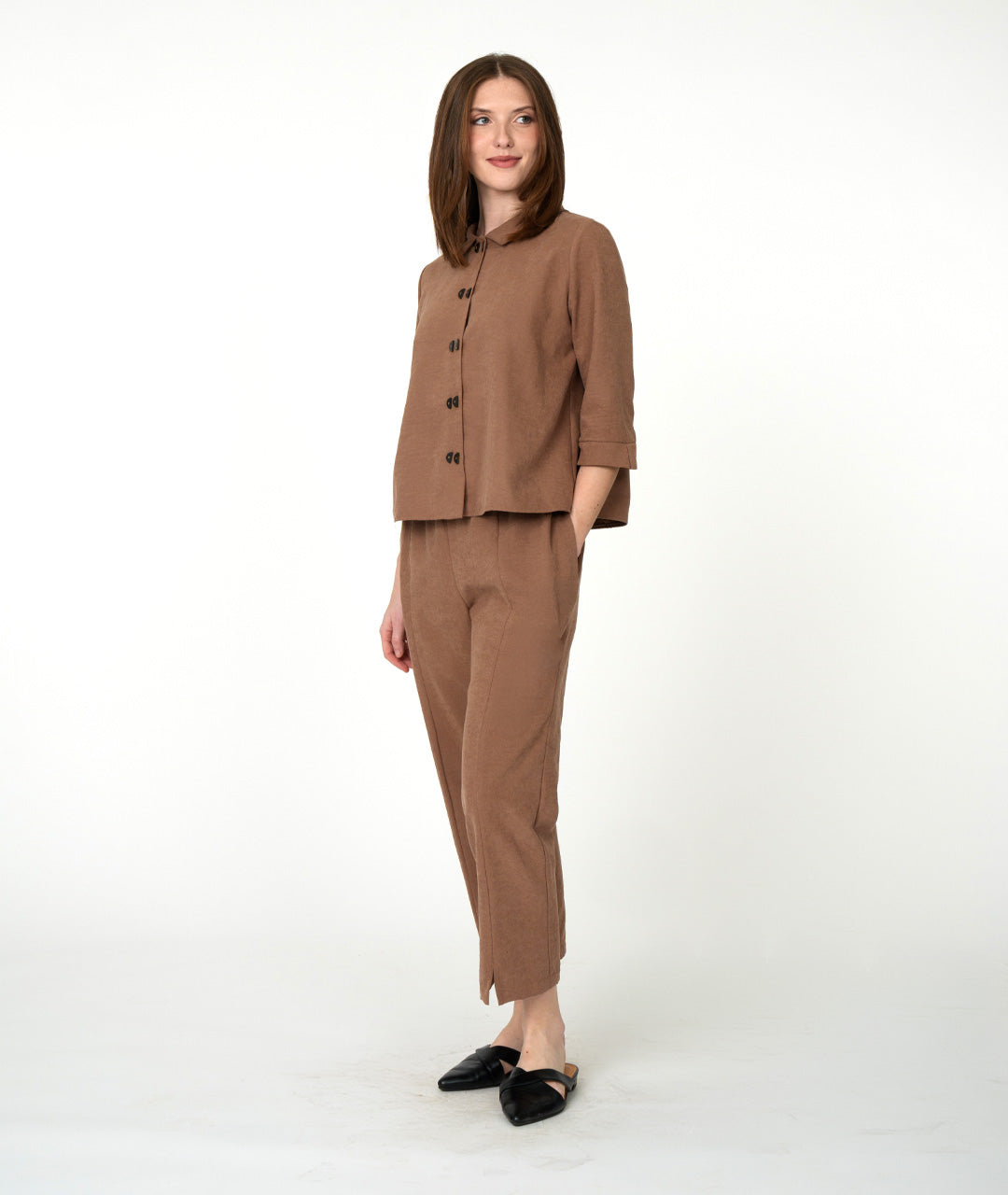 A woman modeling a matching brown two-piece set consisting of a button-front blouse with three-quarter sleeves and straight-leg cropped pants, paired with black flats, against a plain white studio background.