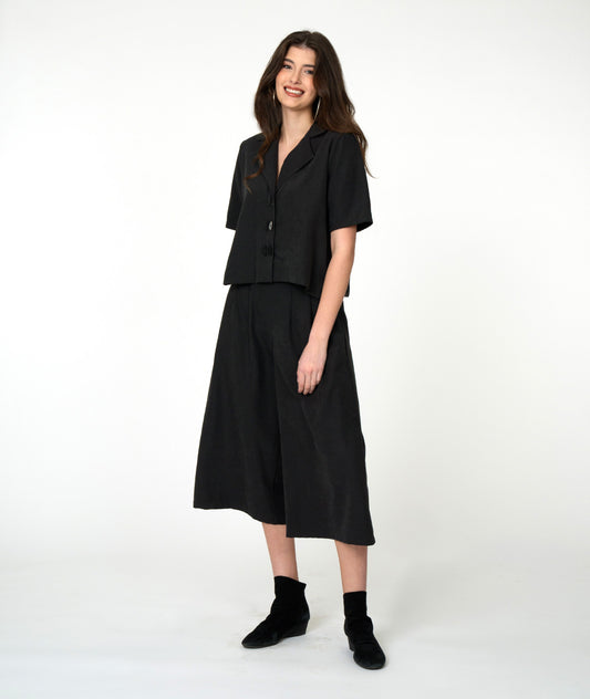 model in a black, boxy button down blouse with matching wide leg pants