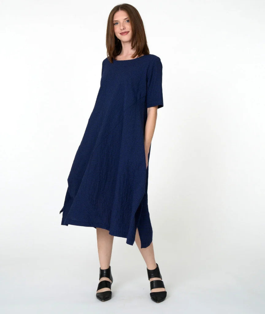 model wearing blue striped dress with mid sleeves and lack shoes against white background