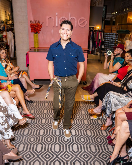 model in a blue shirt and green pants walking down a runway