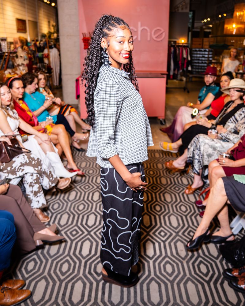 model posing in a checkered button up top and swirl pattern pants on a runway