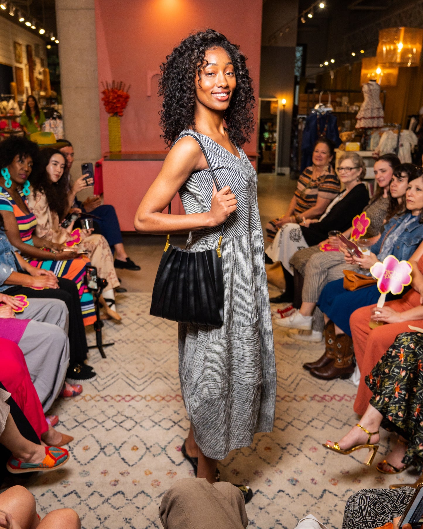 Woman in a black and white stripe dress and black purse walking down runway