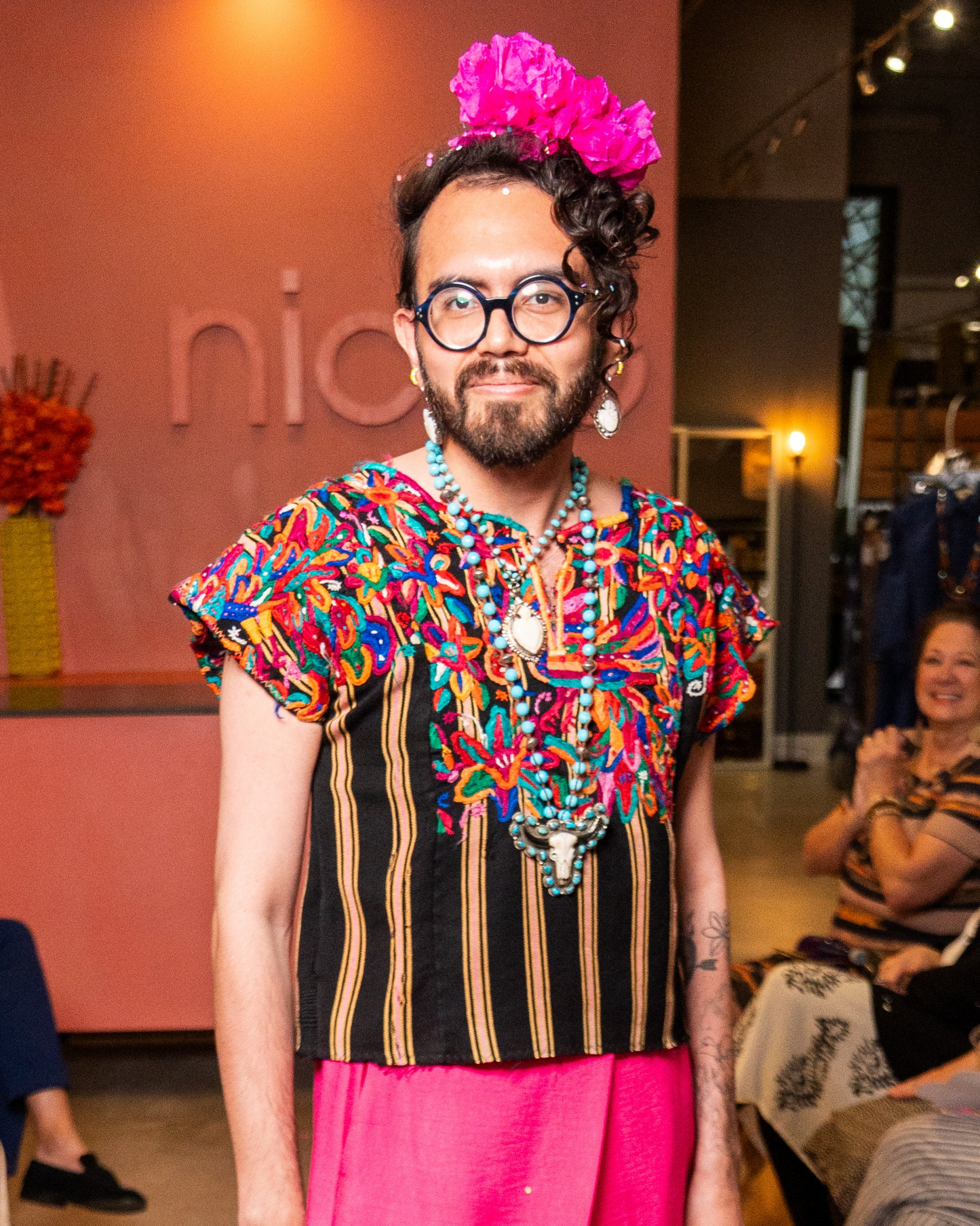 Model wearing colorful top, pink pants and turquoise and bone jewelry