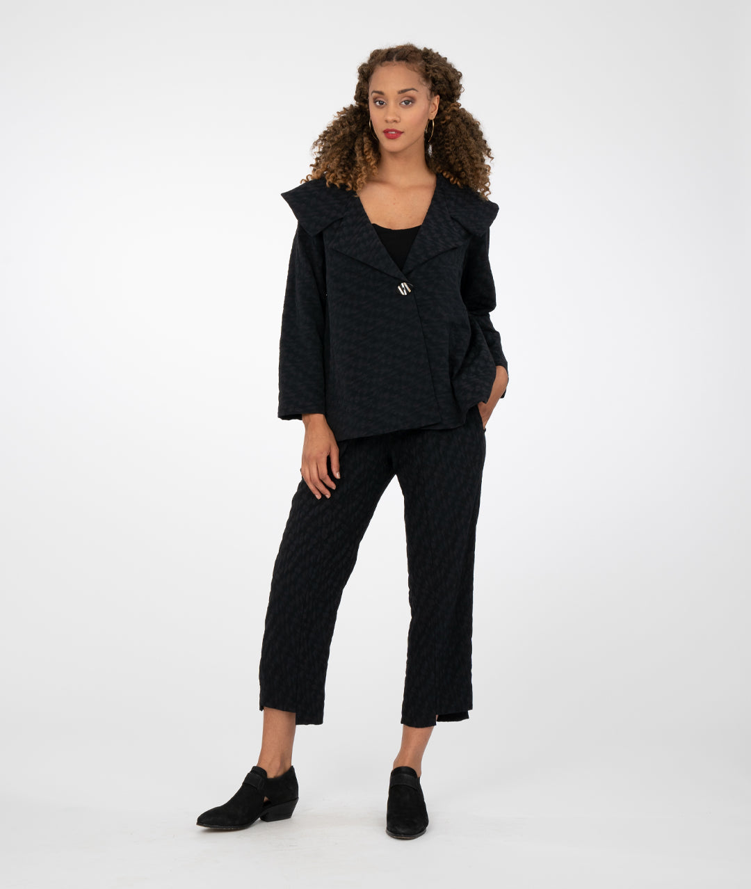 model is wearing all black with black booties against a white background