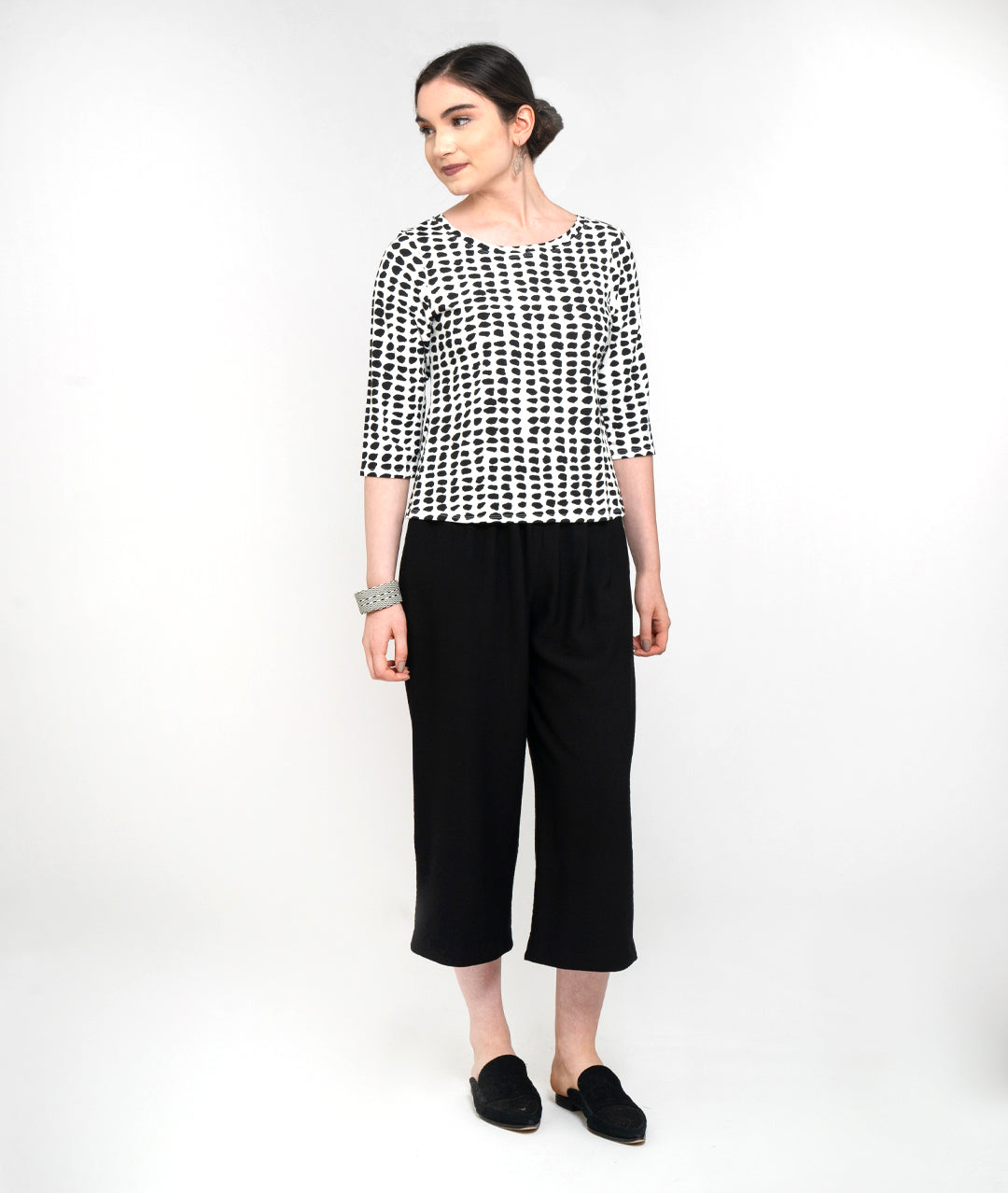 model in a cropped black pant with a black and white dot print pull over tee with 3/4 sleeves