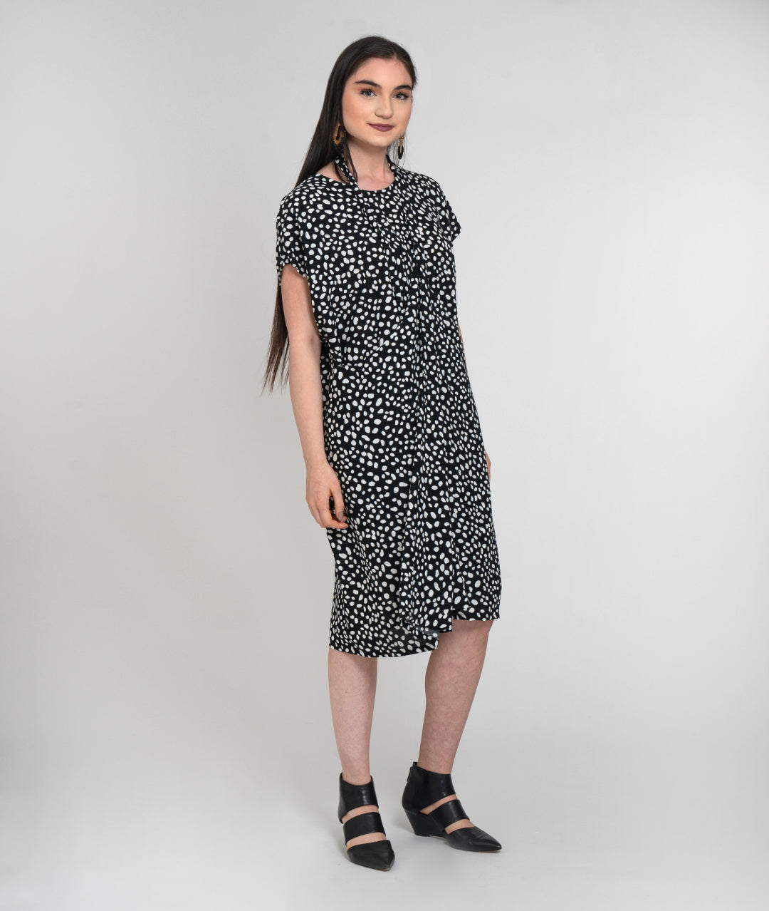 model in a black and white dot print dress with a halter style strap coming from the side panels to around her neck