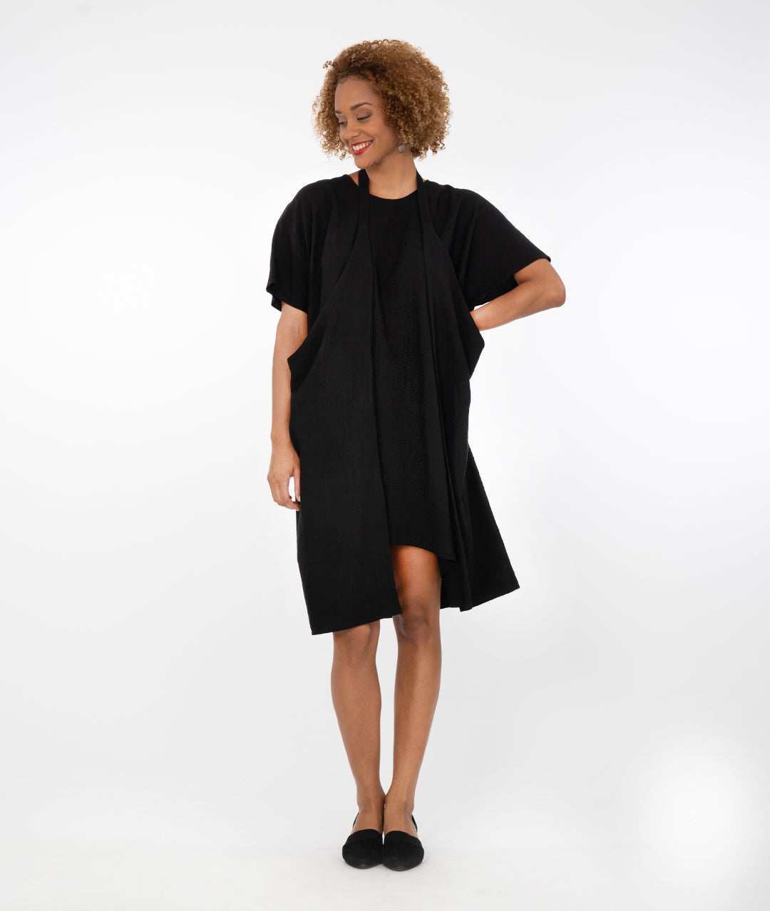 model in a black dress with a halter style strap at her neck in front of a white background