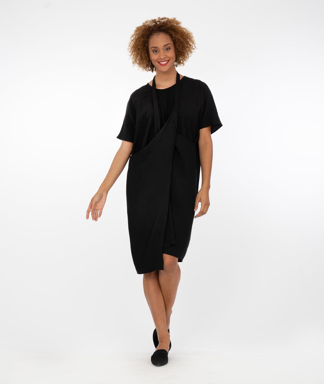 model in a black dress with a halter style strap at her neck in front of a white background