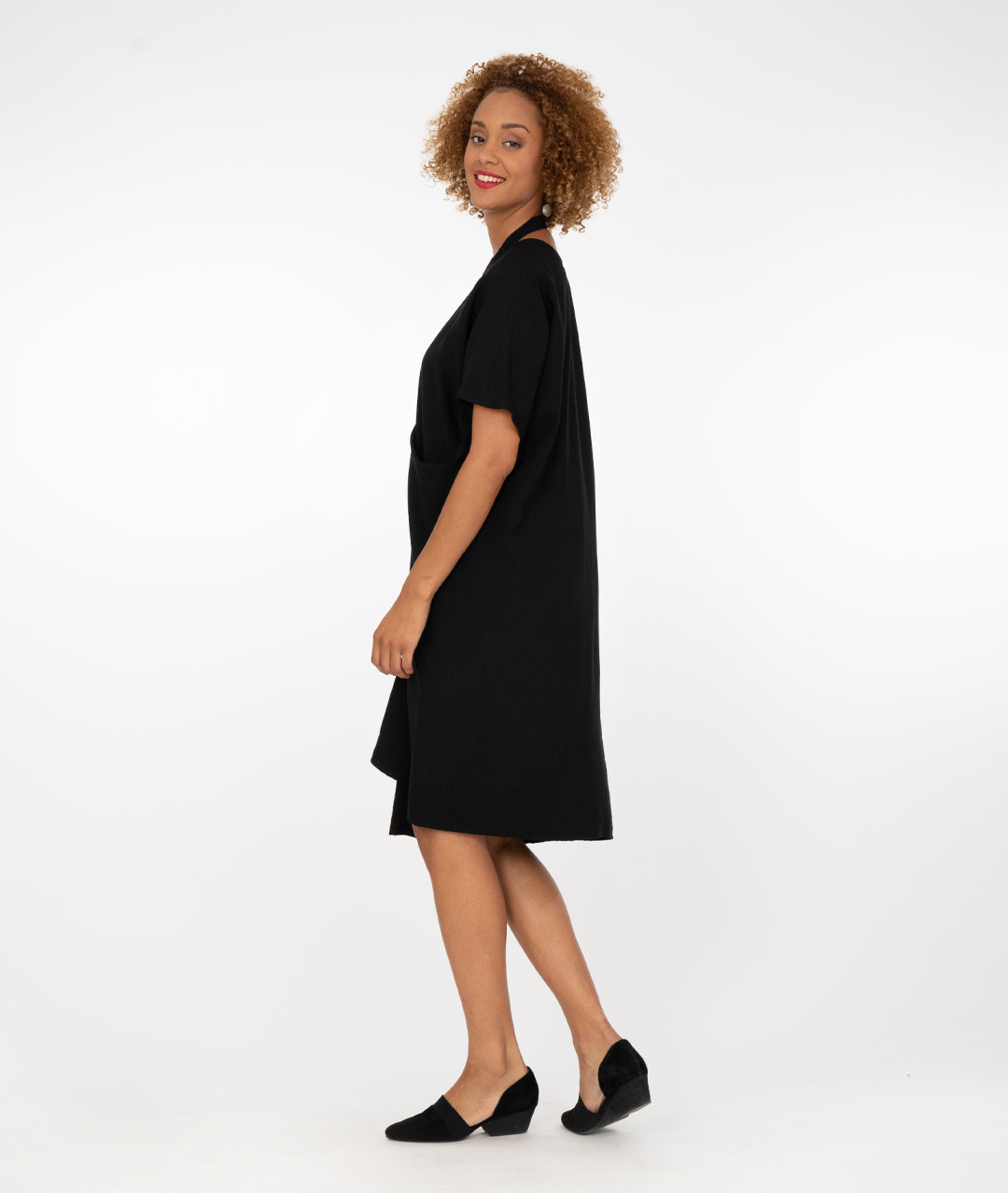 model in a black dress with a halter style strap at her neck in front of a white background