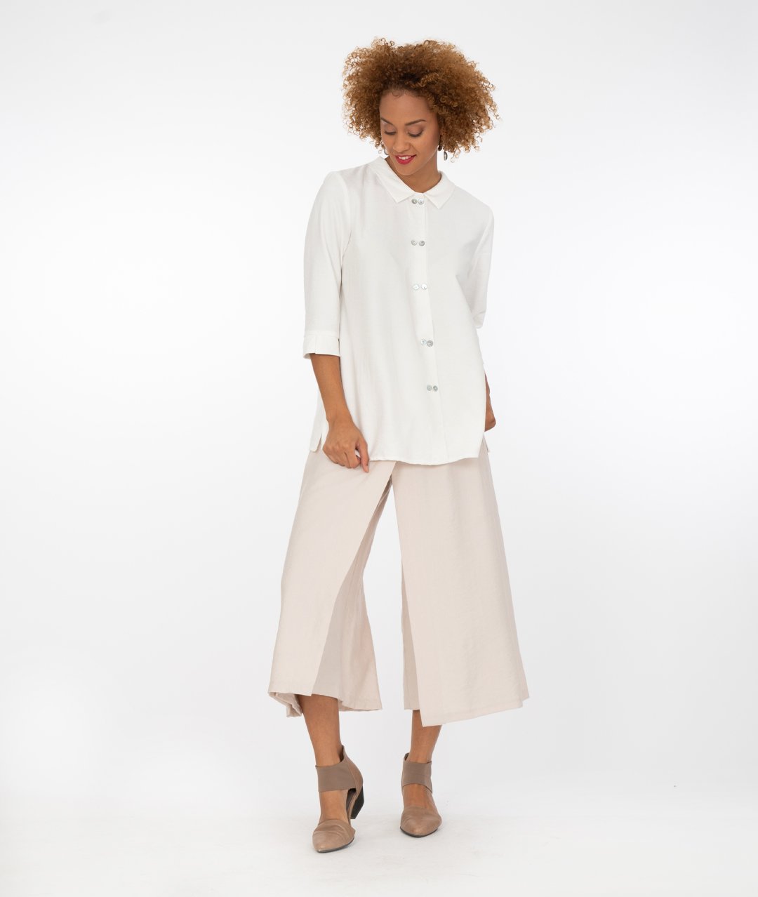 model with a white button up shirt with a wide leg khaki with an overlapping panel in the front on either leg.