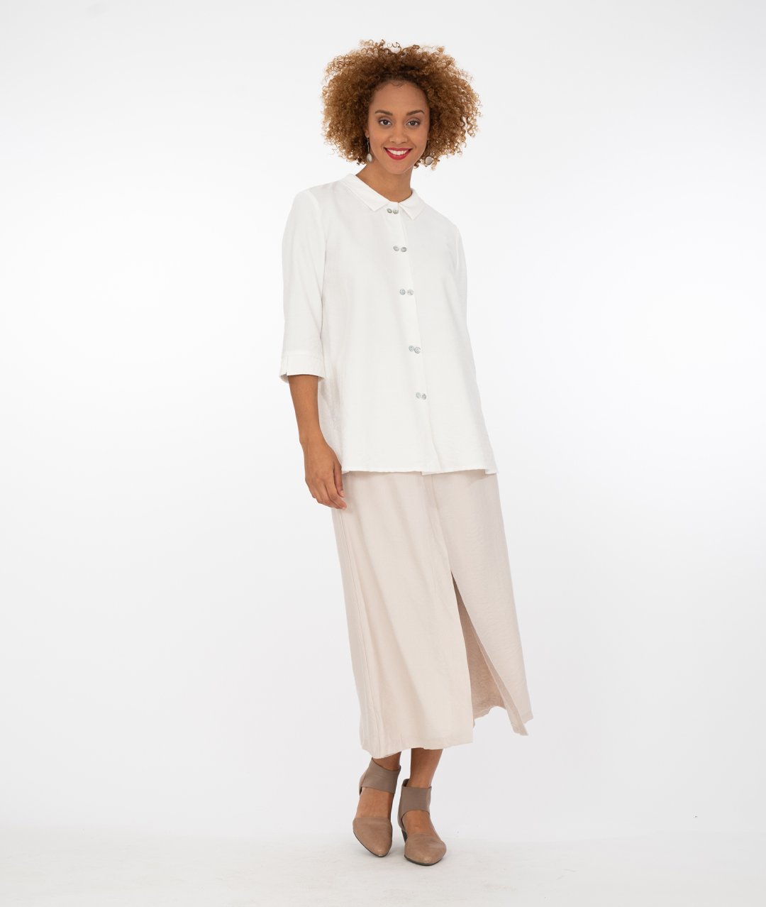 model with a white button up shirt with a wide leg khaki with an overlapping panel in the front on either leg.