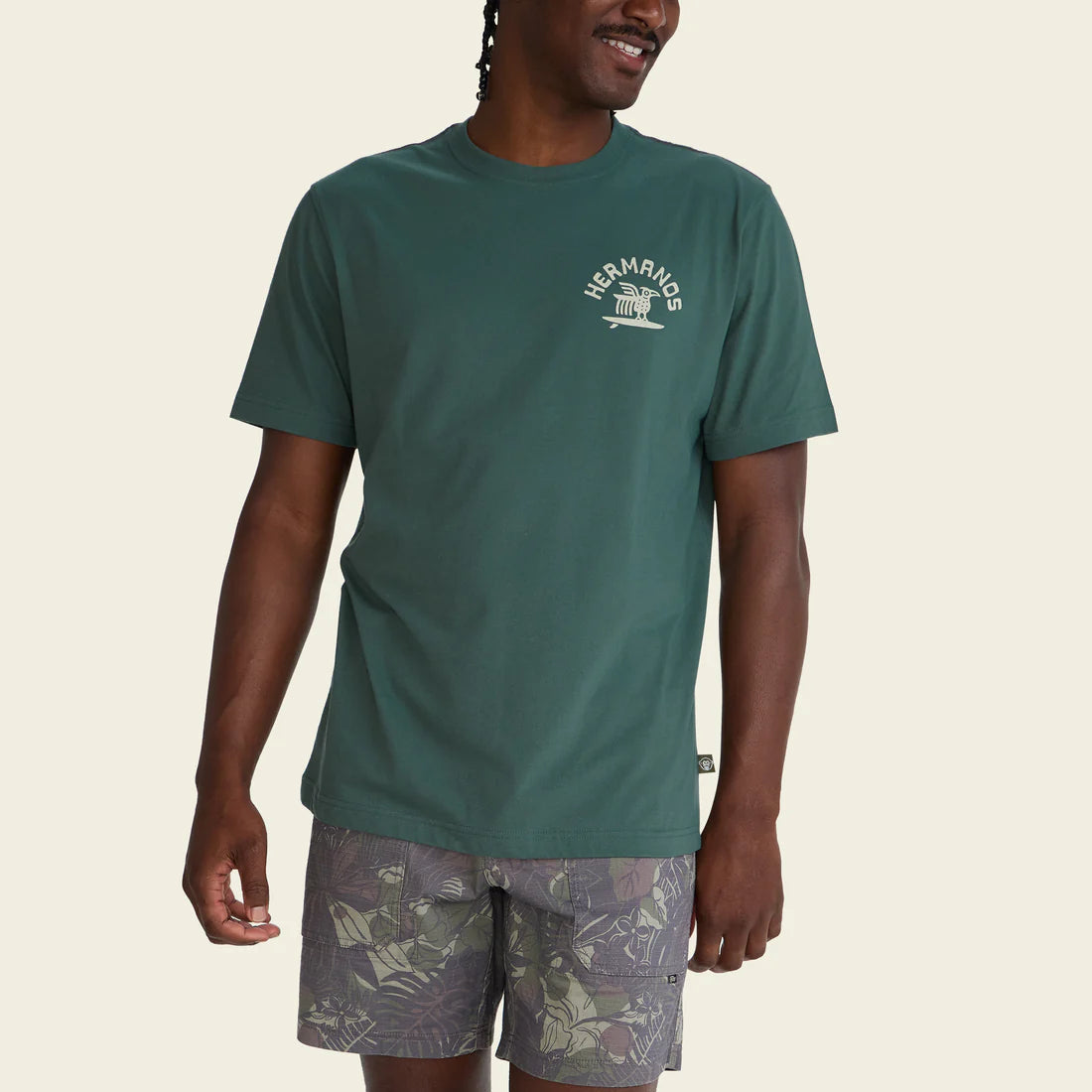 Man wearing a green t-shirt with a logo on a beige background