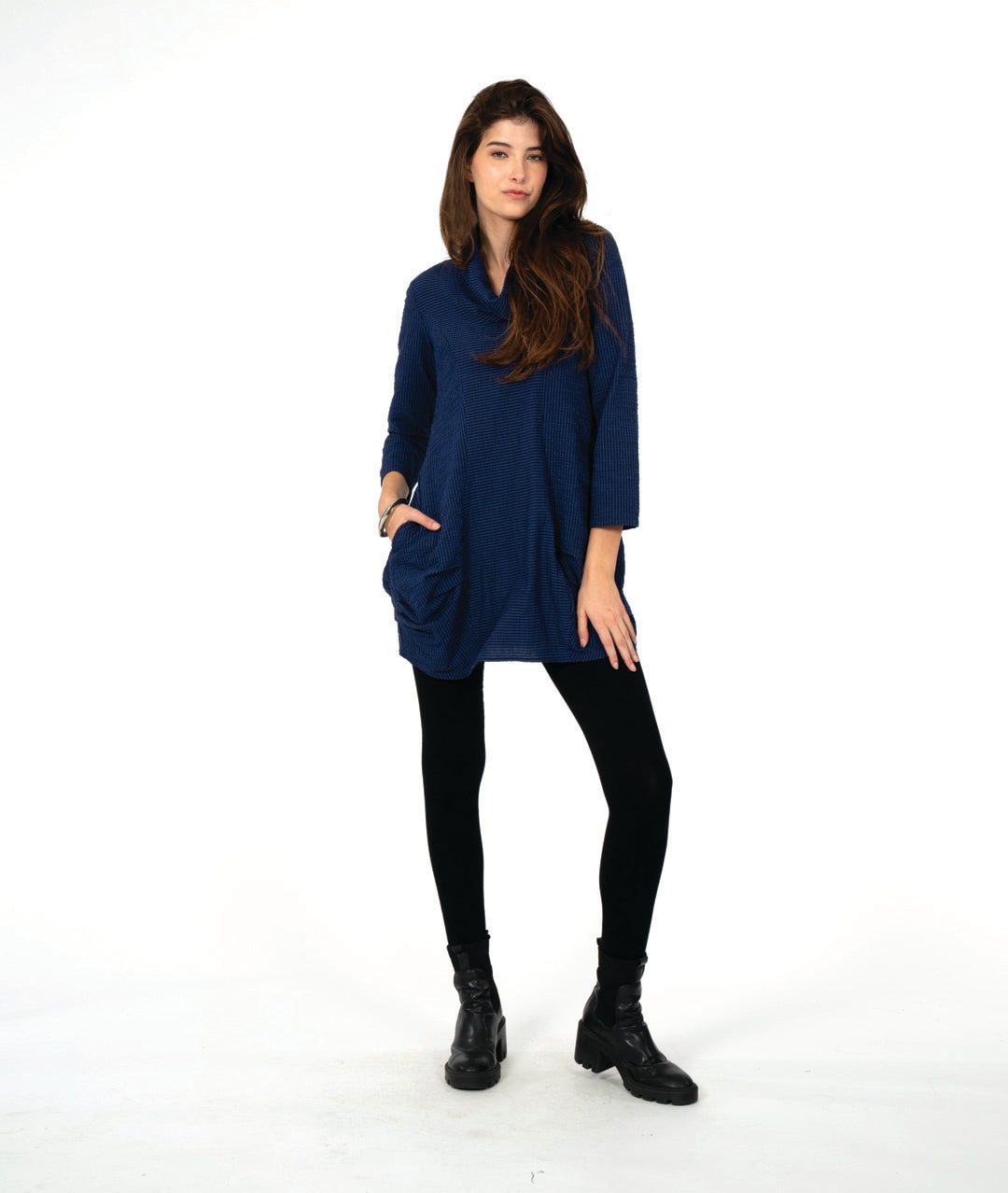 model in a blue and black striped tunic with long sleeves, a cowl neck, and princess seams. hip seams feature large shaping tucks