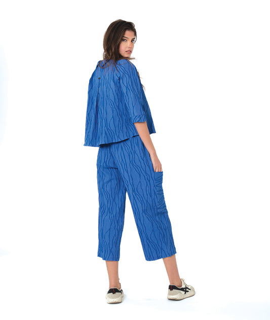 model in a boxy blue button down blouse with a matching straight leg cargo pant.